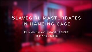 **Slavegirl** engages in **masturbation** within the confines of a **hanging cage**.